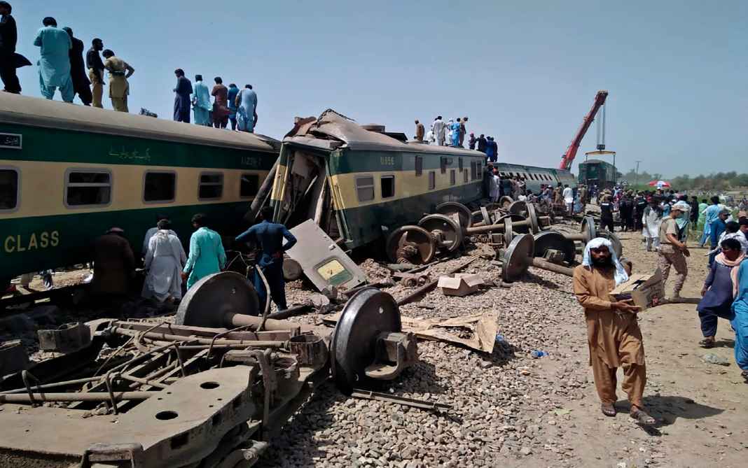 População olha destroços do trem que se acidentou no Paquistão